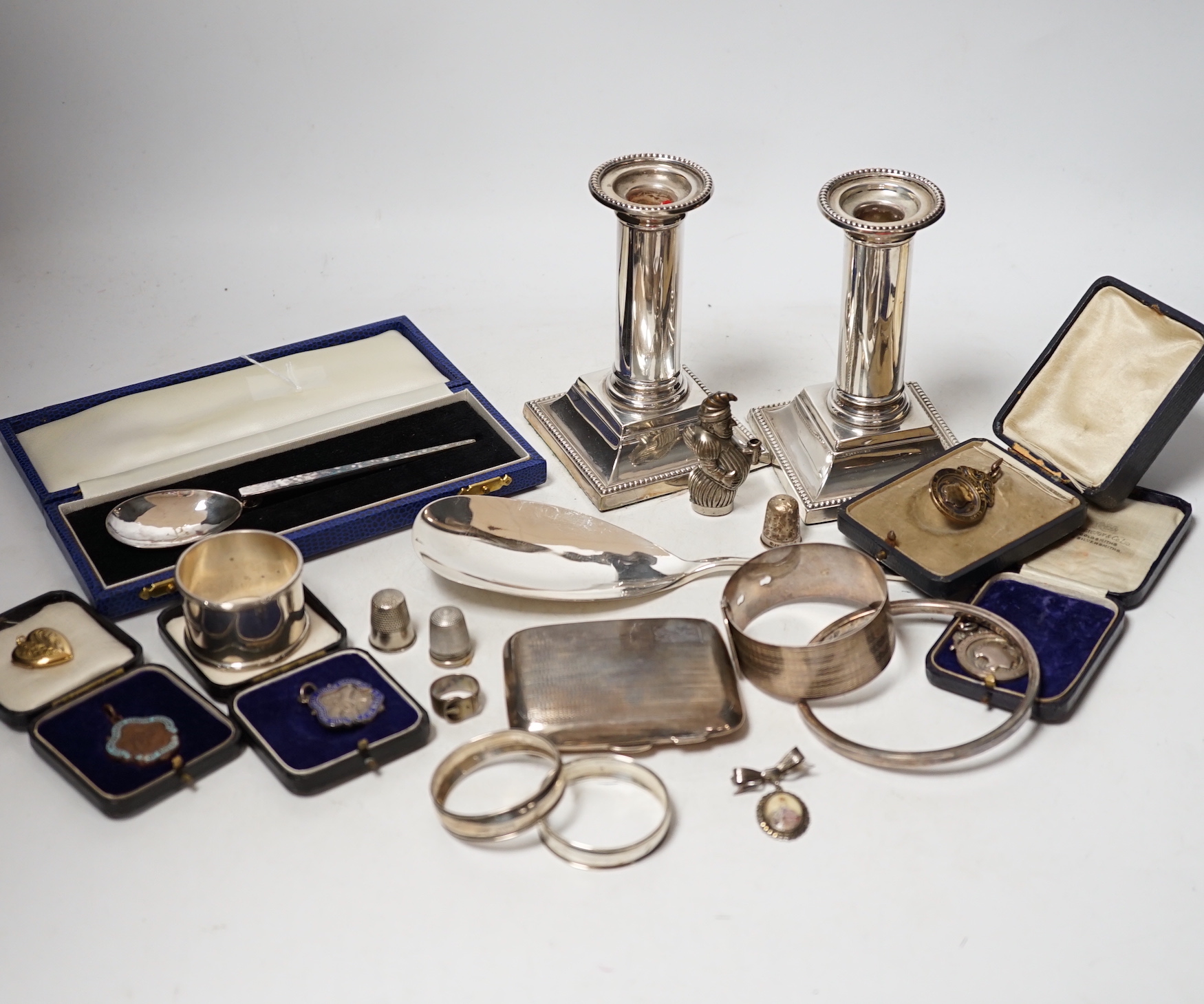 Sundry small silver including a cased preserve spoon, by Albert Edward Jones, a pair of mounted dwarf candlesticks, serving spoon, thimbles, napkin ring etc.